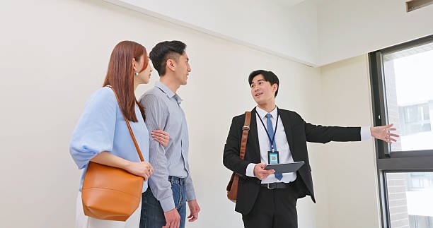asian male real estate agent using tablet to show a young couple the house
